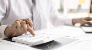 persona che calcola paghe con calcolatrice e documenti