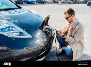 persona che usa smartphone con auto elettrica vicino