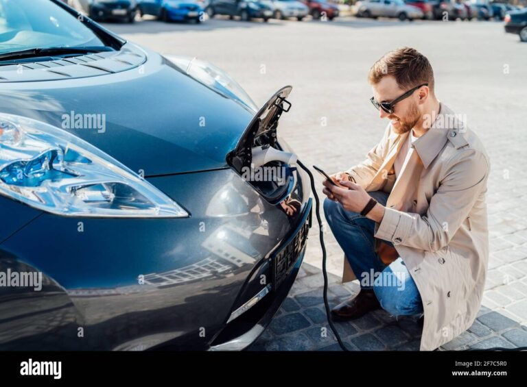 persona che usa smartphone con auto elettrica vicino