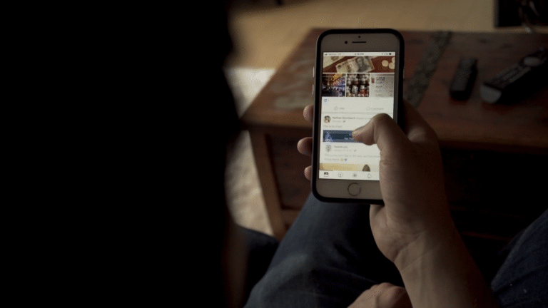 persona che usa smartphone con facebook aperto