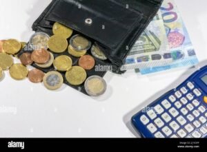 portafoglio con banconote e monete accanto a calcolatrice